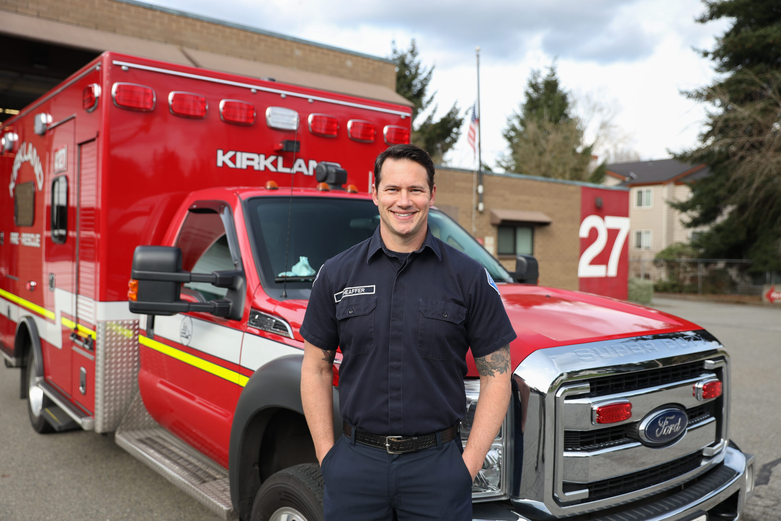 Ryan dressed in his EMT uniform standing in front of a red fire truck