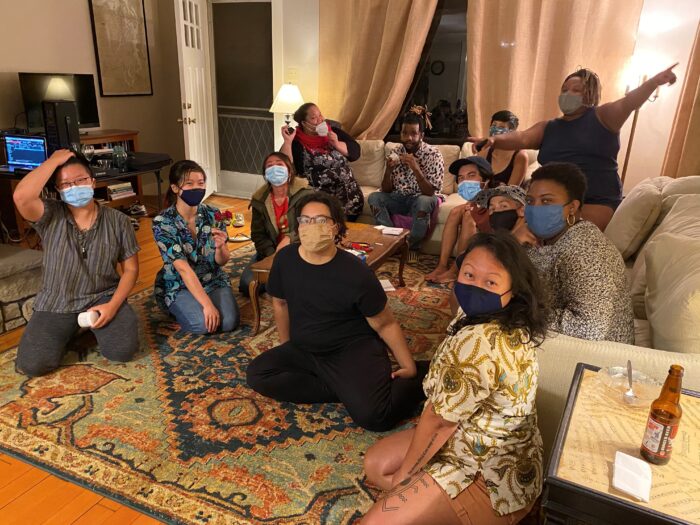 Twelve people from the Queer the Land community sitting on the floor and on couches at a retreat in September 2020