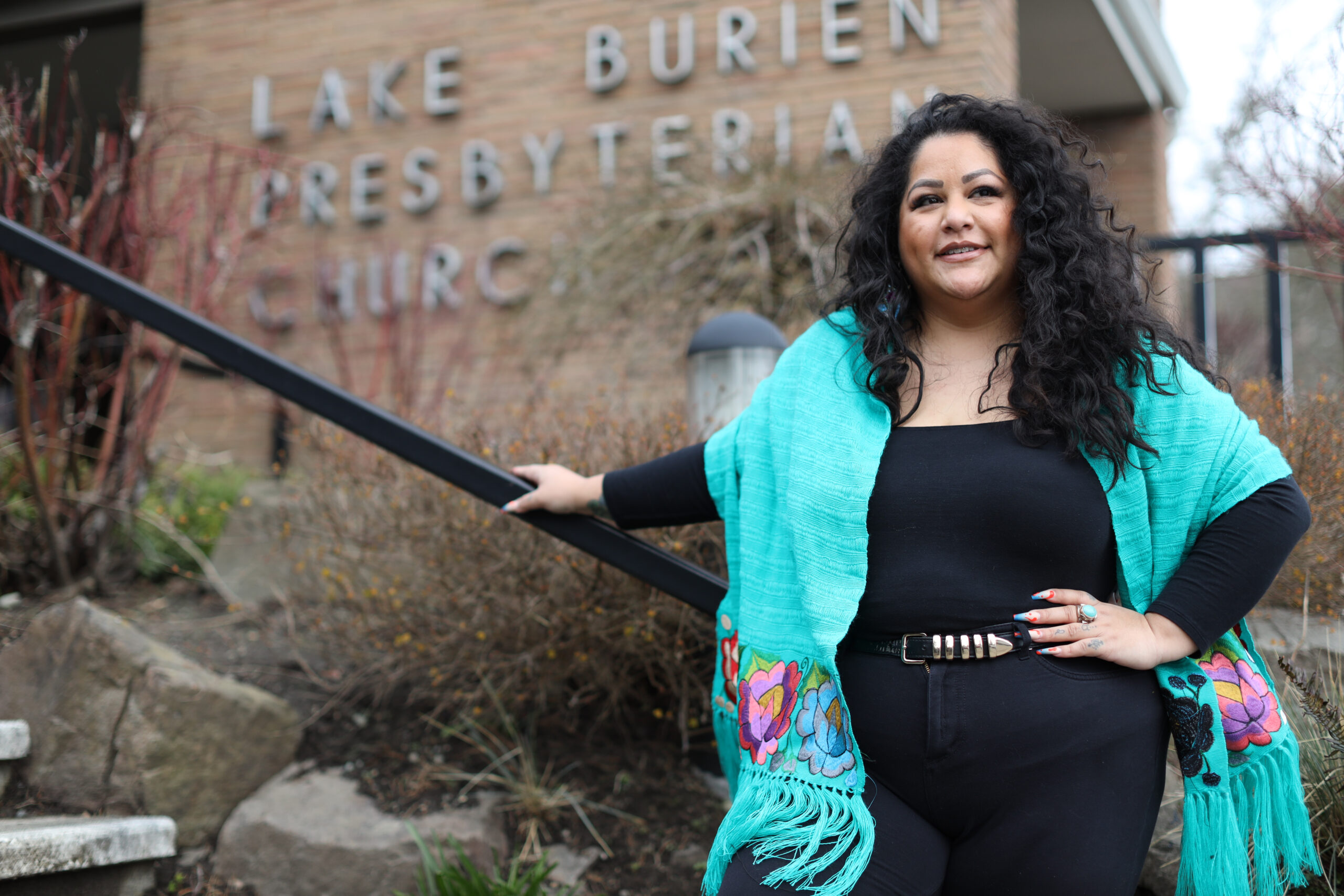 http://Roxana%20wearing%20a%20turquoise%20shawl,%20black%20pants%20and%20top%20standing%20on%20the%20steps%20of%20the%20Lake%20Burien%20Presbyterian%20Church