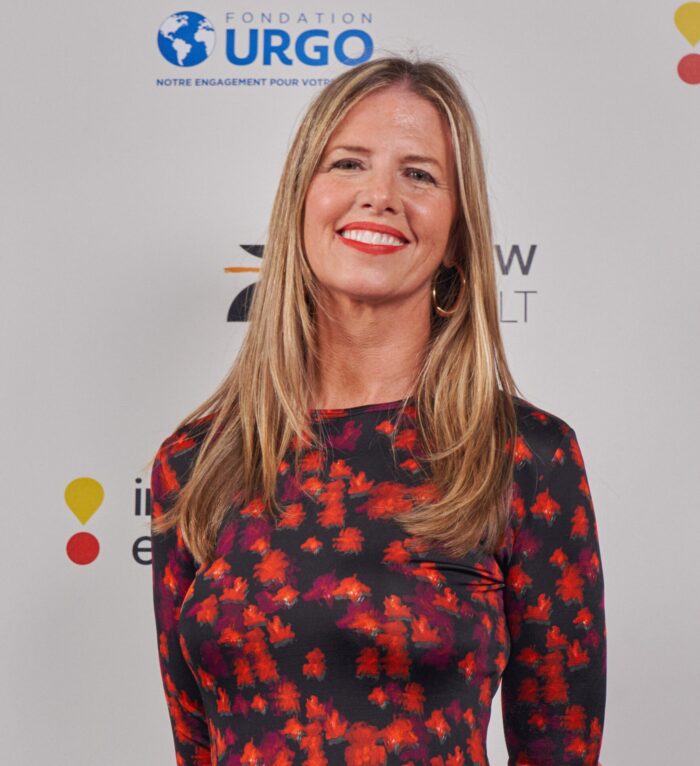 Shannon Cohn in a black and red floral dress smiling at the camera with a white background.